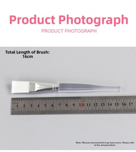 Flat lay detail showing a 16cm transparent acrylic facial mask brush with synthetic bristles