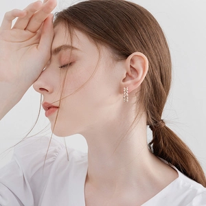 Elegant C-shaped gold hoop earrings with inlaid pearls worn by a model in a side profile