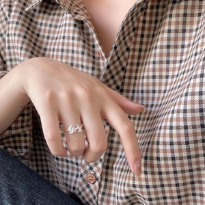 Detailed view of an adjustable silver rose ring with petal textures on a finger