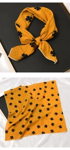 Détail d'un foulard carré jaune en coton et soie avec motif trèfle noir et nœud noué