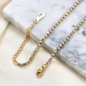 Detailaufnahme des 18KGP-Stempels auf verstellbarer goldener Tenniskette auf Marmor