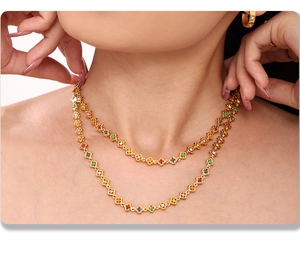 Close-up of double-layered gold necklace with colorful flower charms and gemstones