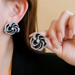 Detail of black swirl flower earrings with sparkling rhinestones worn by a model