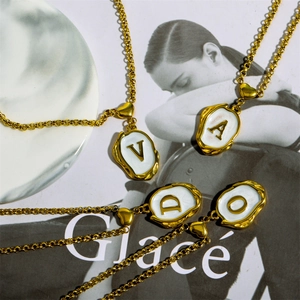 Close-up of 18K gold plated necklaces featuring white enamel 26 letter pendants