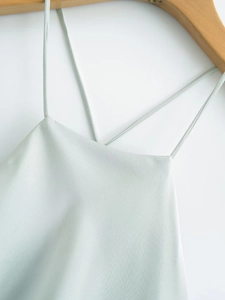 Detail of mint green satin camisole top with thin straps on a wooden hanger