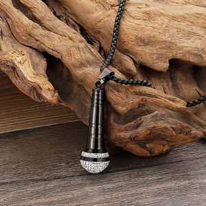 Macro view of black 18K titanium steel microphone pendant on textured weathered wood
