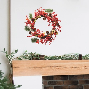 Christmas wreath with red berries, pine cones and green needles on white wall