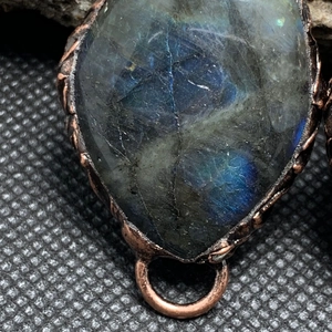 Macro shot of vintage bronze teardrop labradorite pendant with blue labradorescence