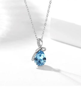 Macro shot of silver-tone teardrop pendant with blue crystal and white stones inlay