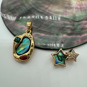 Macro detail of gold-plated abalone shell pendant with sparkling star zircon inlay
