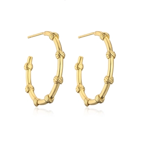 Detailed close-up of C-shaped golden earrings with bamboo texture and metallic finish