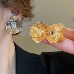 Detailed view of brushed metal flower earrings in gold and silver finishes