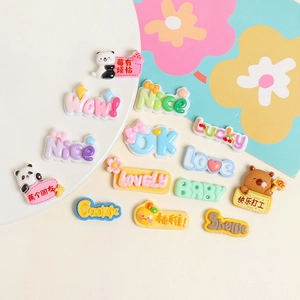 Flat lay of resin charms featuring cartoon pandas, animals, and colorful English letter tiles