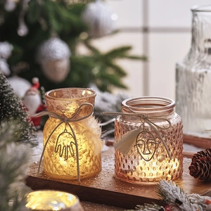 Luminous Christmas glass candle holders with warm LED lights on a rustic wooden base