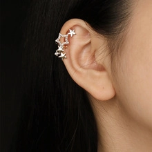 Close-up of star-shaped silver ear cuff with sparkling rhinestones on model's ear