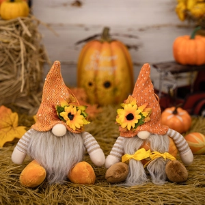 Close-up of autumn gnomes with orange knit hats and sunflower details on hay