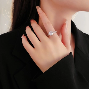 Close-up of elegant hollow silver ring with round zircon worn by a model in black