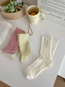 Detail of three pairs of ribbed cotton mid-calf socks in pink, green, and cream colors