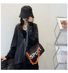 Détail du sac cylindre noir en nylon avec chaîne orange et logo Sport imprimé