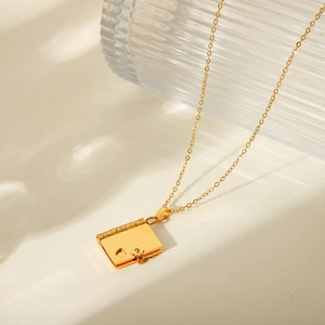 Close-up of golden book-shaped locket pendant with heart cutout on necklace