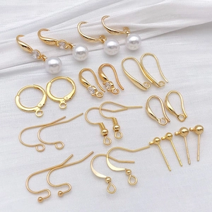 Golden DIY jewelry earring hooks and pearl pendant components on white silk