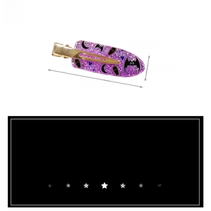Detailed view of a purple glitter Halloween hair clip featuring a bat and coffin motif