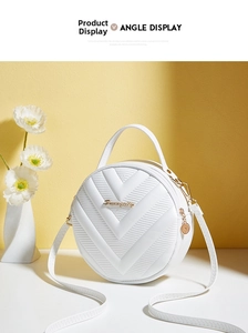 Detail of white round crossbody bag featuring V-shaped quilting and gold metal logo charm