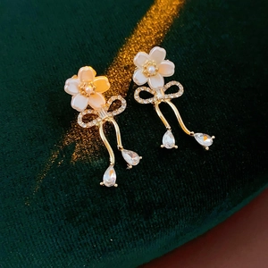 Détail des boucles d'oreilles fleurs avec nœuds dorés et cristaux en goutte