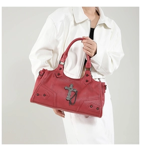 Detail der roten Punk-Handtasche mit Nieten und Kreuzanhänger auf weißer Jacke