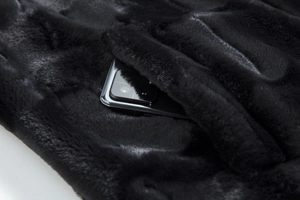 Close-up of plush faux fur coat pocket showing depth with a smartphone inside