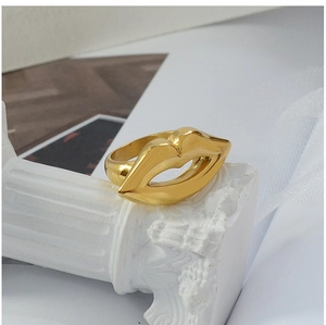 Artistic close-up of a 18K gold-plated lip-shaped ring on a white decorative pillar