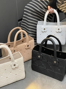 Dettaglio borse da mare in EVA nei colori nero, bianco e beige con fibbie a fiore