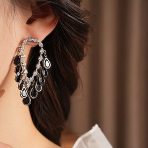 Close-up of sparkling zirconia tassel earrings with black teardrop stones on model