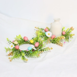 Detail of Easter candle rings with pastel eggs and white daisies on woven green leaves
