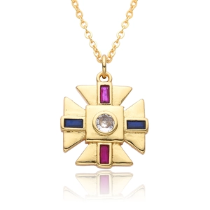 Detailed macro view of gold cross pendant with ruby and blue faceted gemstones