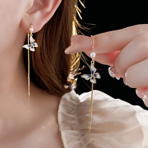 Detail of butterfly tassel earrings with 14K gold plating, enamel and white pearl accents