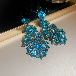 Close-up of sparkling blue crystal flower drop earrings with starburst light effect