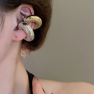 Détail macro des boucles d'oreilles dorées et argentées avec motif alvéolé sur l'oreille