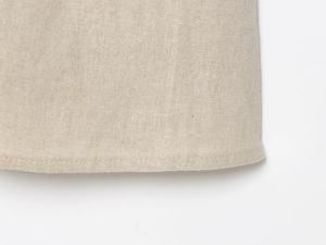 Macro view of linen dress hem showing detailed stitching and natural fabric texture