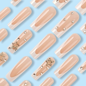 Long French press-on nails in nude pink with white tips, silver stars and rhinestones