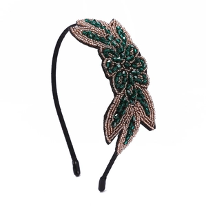 Macro detail of handmade dark green and bronze beaded leaves on a retro style headband