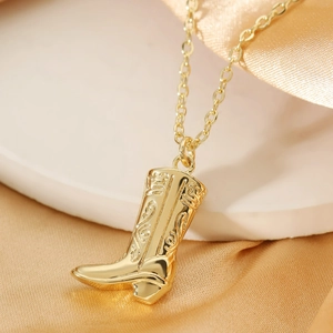 Close-up of golden western cowboy boot pendant with detailed floral embossing