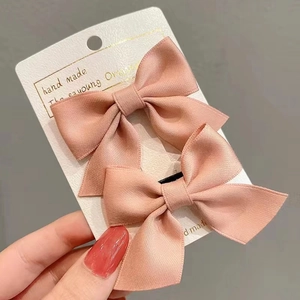 Close-up of handmade pink ribbon bow hair clips set on original display card