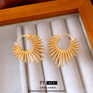 Exaggerated gold sunburst hoop earrings with radiant metal lines in jewelry box