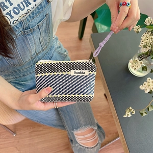 Detail of color-block woven mini pouch with purple wrist strap and Sozakka label