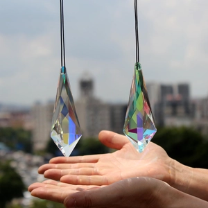 Close-up of two K9 crystal suncatcher prisms with rainbow luster hanging on black ropes