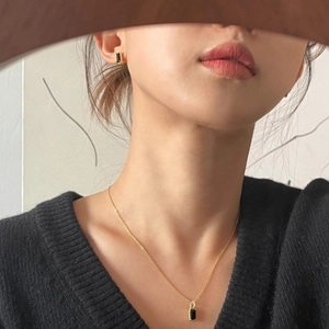 Detail of 925 silver gold necklace and black rectangle pendant worn by model