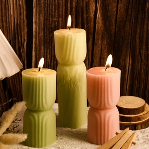 Dettaglio di candele pilastro geometriche a coste nei toni verde salvia e crema