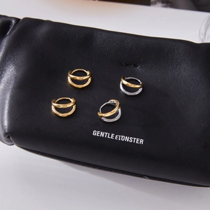 Detail of two-tone and gold double-layer hollow earrings on black leather texture