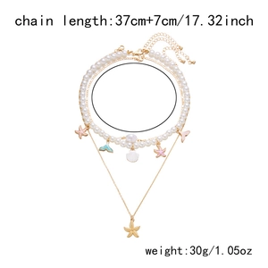 Detail of layered gold necklace with shell and starfish charms including size and weight info